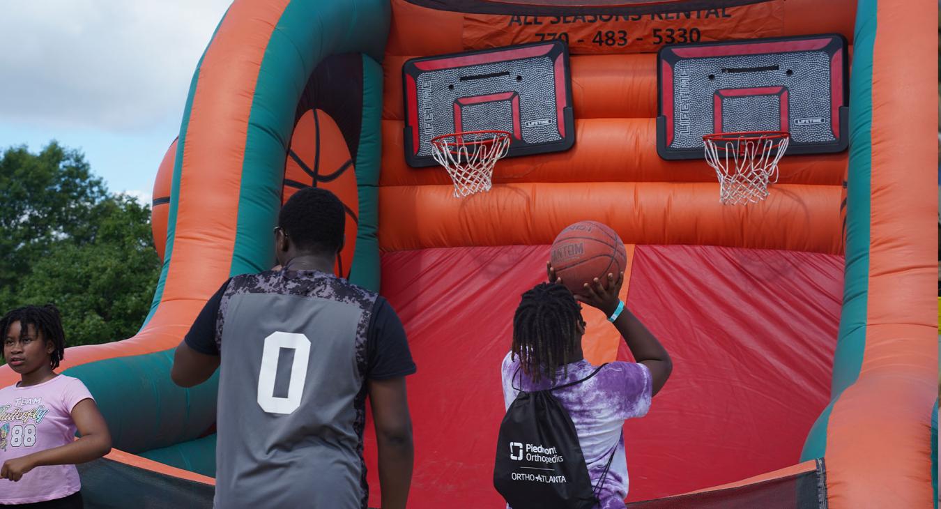 Children play basketball before meeting